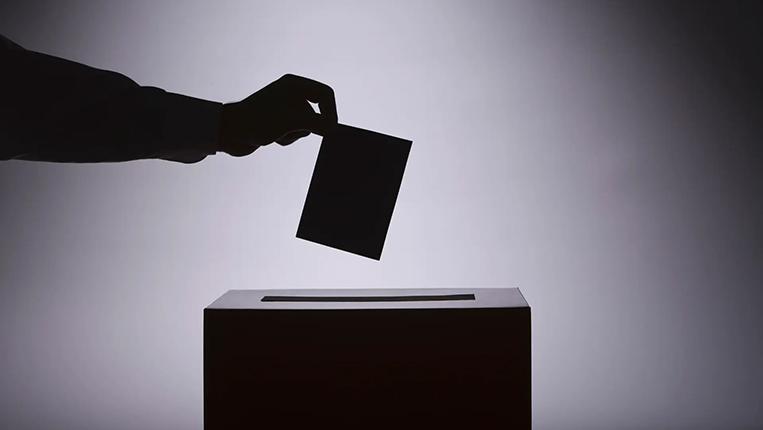 Sinueta de mão a colocar um voto na caixa de voto.
